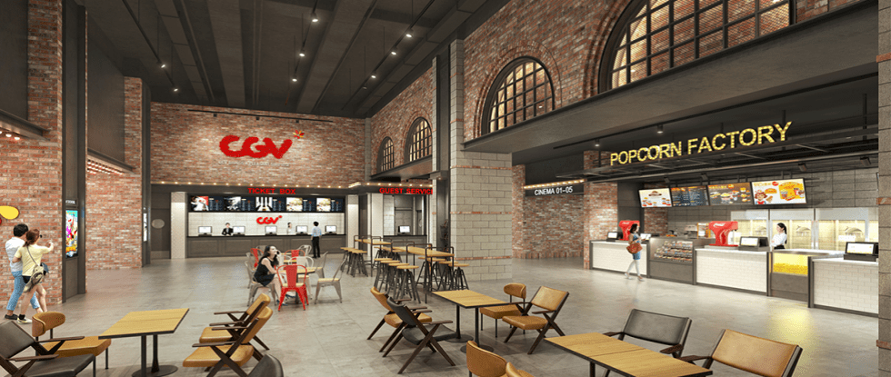 Interior of a movie theater lobby with a CGV ticket counter, guest service desk, and a popcorn factory concession on the right; tables and chairs scattered throughout the space.