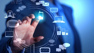 Businessperson taps a glowing circle of floating icons representing connectivity: devices, messages, and servers.
