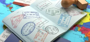 Open passport covered with colorful visa stamps resting on a world map background.