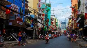 Colorful street in Vietnam with numerous flags, scooters, pedestrians, and a red bus in the distance.]** Note: remove this line