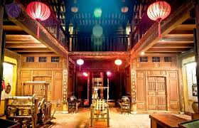Traditional wooden interior with carved doors, low tables, and red paper lanterns hanging from the ceiling under warm lighting.