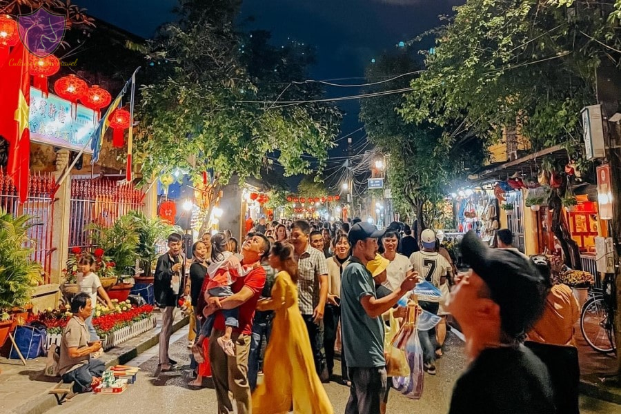 Night street market at night with red lanterns, illuminated stalls, and a crowd of shoppers.