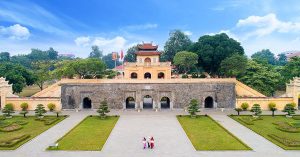 Historic stone fortress with arched doorways and a yellow pavilion on top, set in a manicured garden with trees nearby.