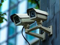 Two outdoor security cameras mounted on a wall, angled to surveil the surrounding area.