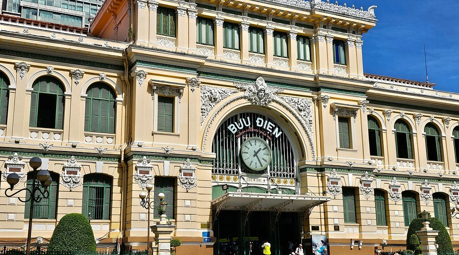 Grand historic post office-style building with an ornate cream façade, arched windows, and a central clock above the entrance