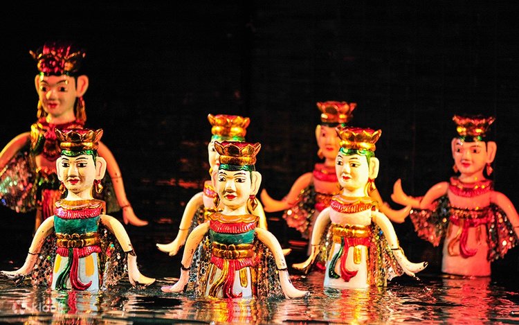 Colorful traditional puppets with crowns arranged in shallow water on a dark stage, prepared for a performance.