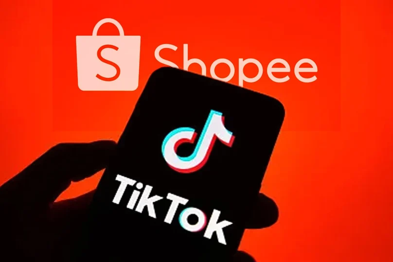 Phone screen showing the TikTok logo in front of a bright Shopee brand backdrop, suggesting social shopping.