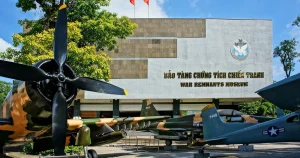 Front view of the War Remnants Museum with vintage military aircraft parked outside and a large propeller in the foreground.
