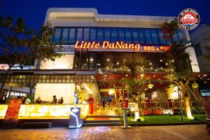 Front of Little DaNang BBQ & Pub at night with neon orange sign and warm-lit outdoor seating patio.